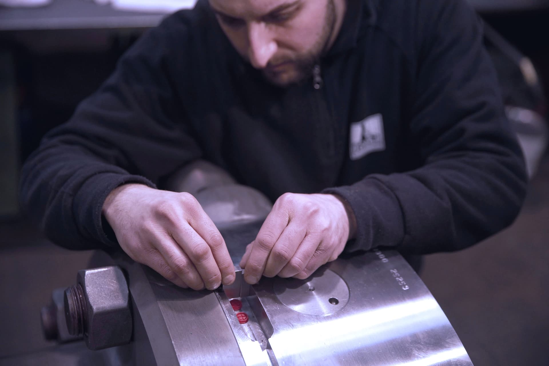 Technician working carefully on a steel component with his hands