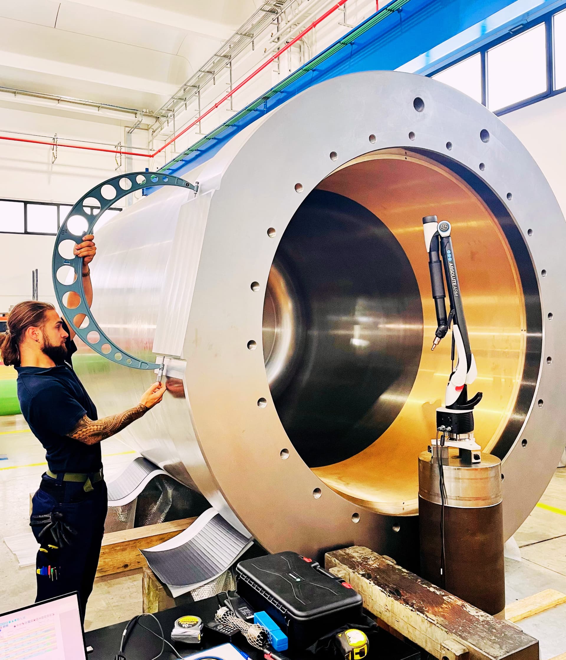 Technician measuring the bore of a very large steel cylinder with an arc gauge and a measuring arm