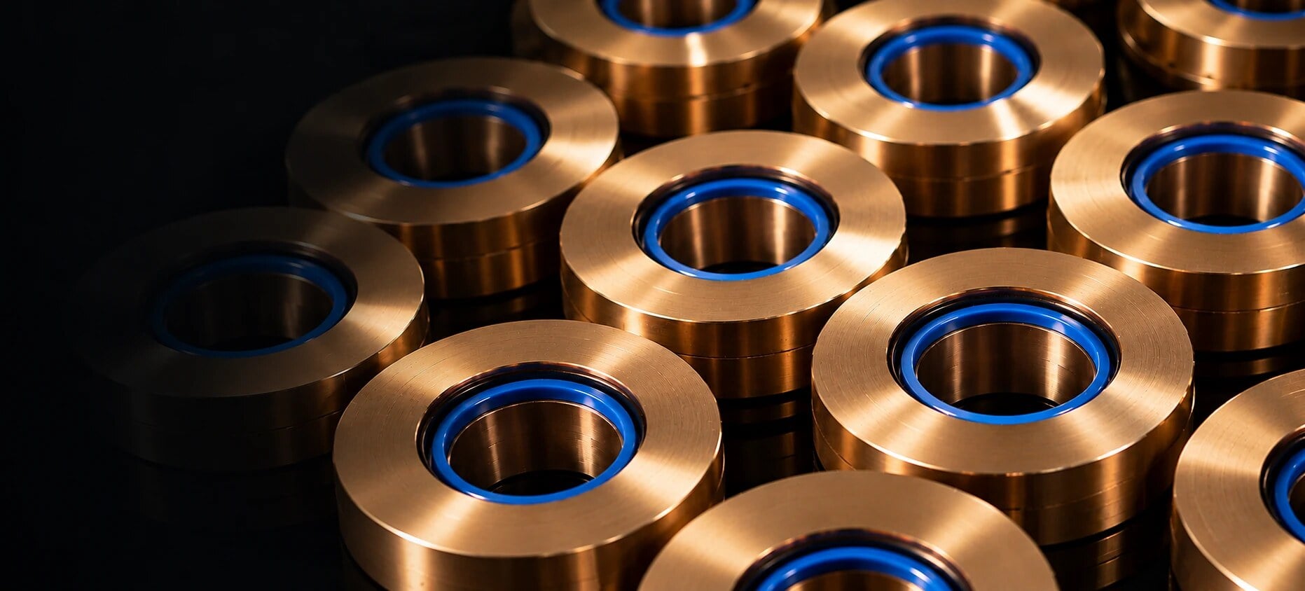 Bagues de guidage en bronze avec joints bleus en polyuréthane sur une surface sombre réfléchissante