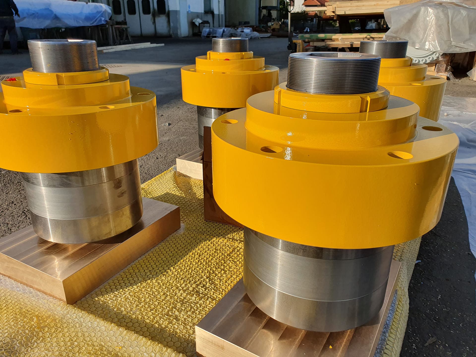 Yellow cylinder heads with polished steel rods on wooden blocks
