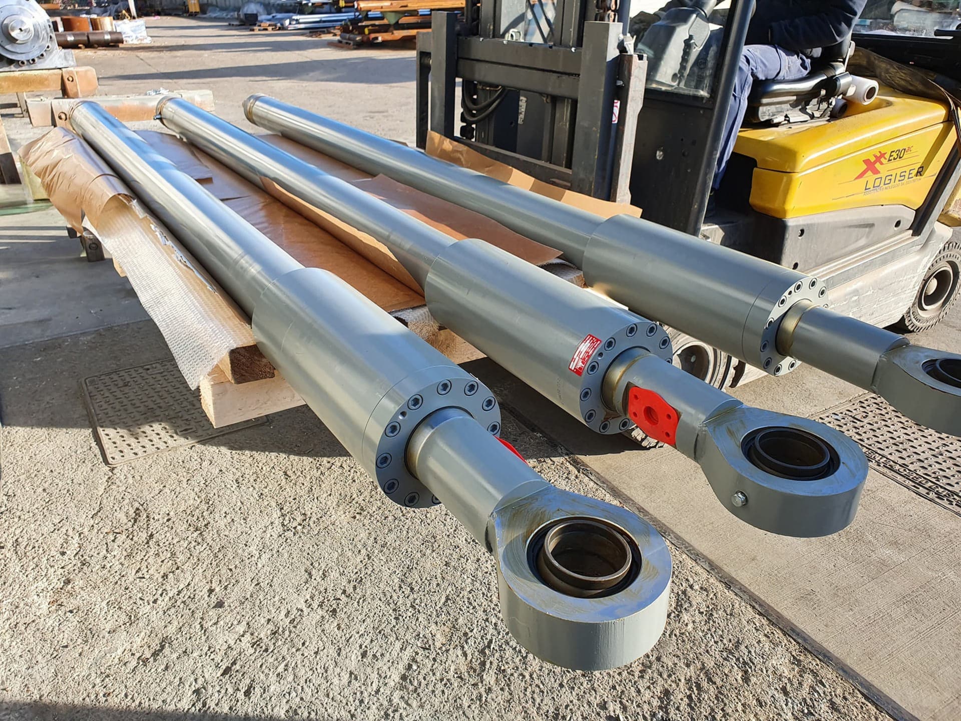 Three long cylinders with rod-end eyes on a pallet