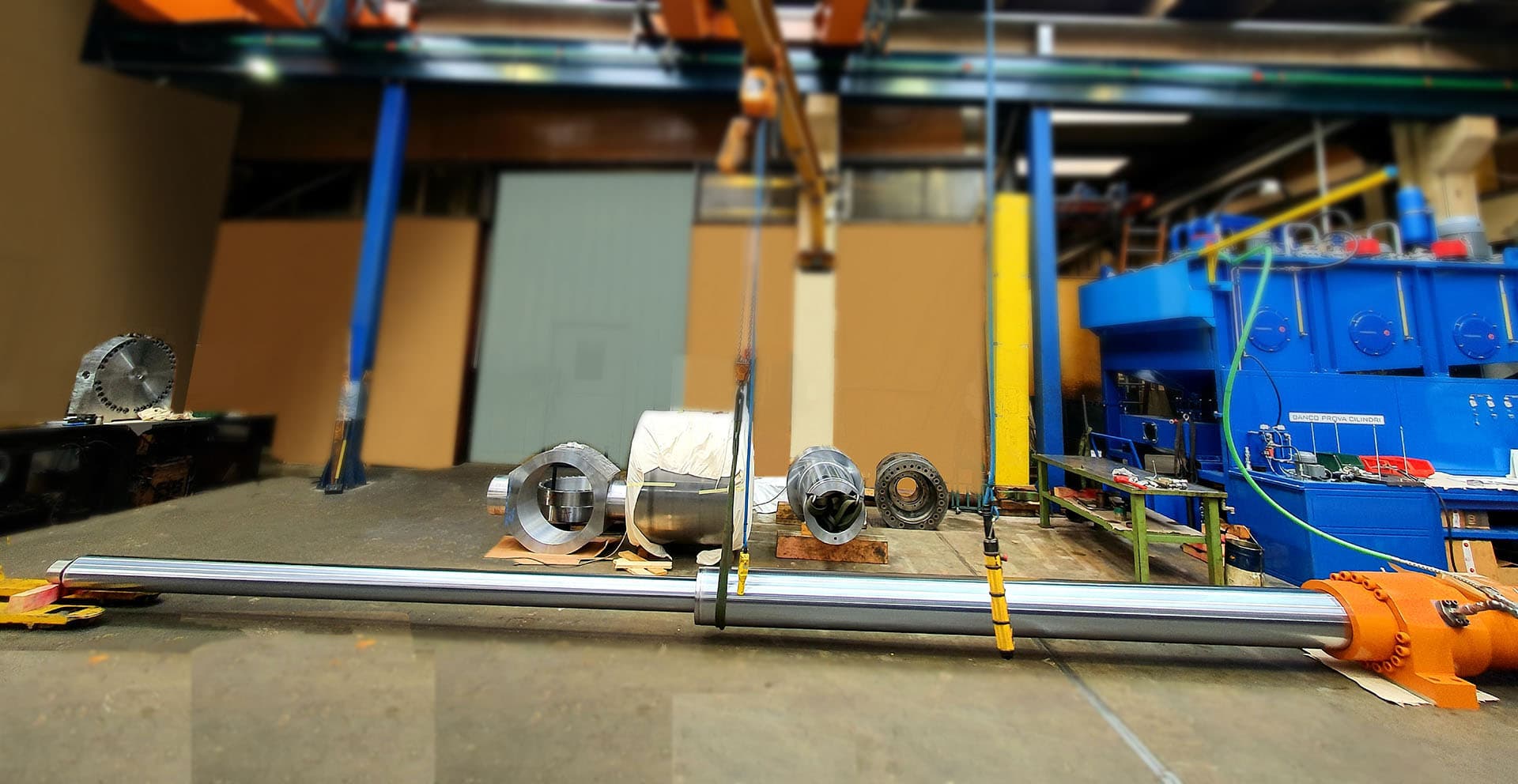 Long chrome tube on the floor of a workshop with parts in the background