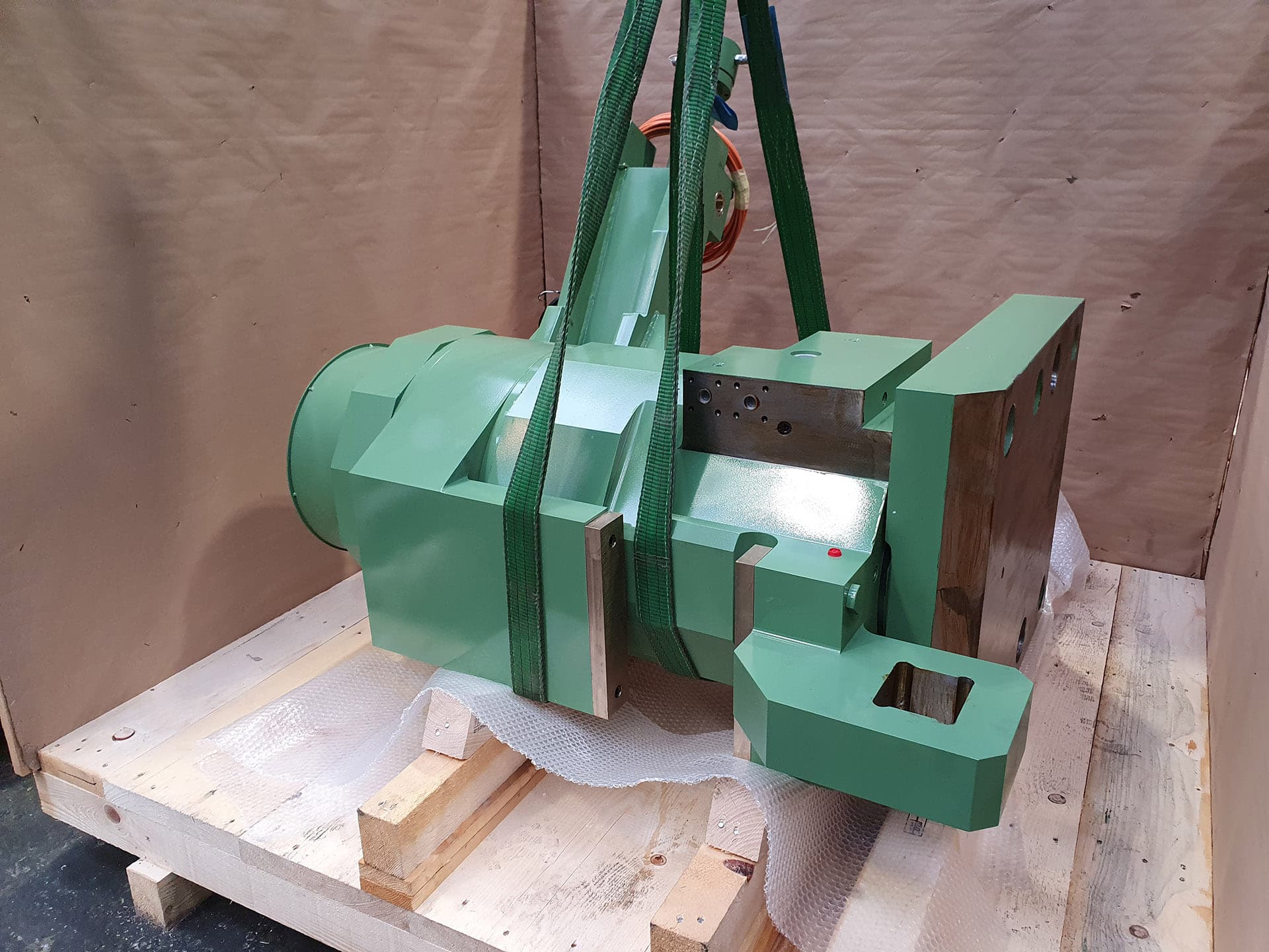 Green cylinder body secured on wooden supports inside a shipping crate