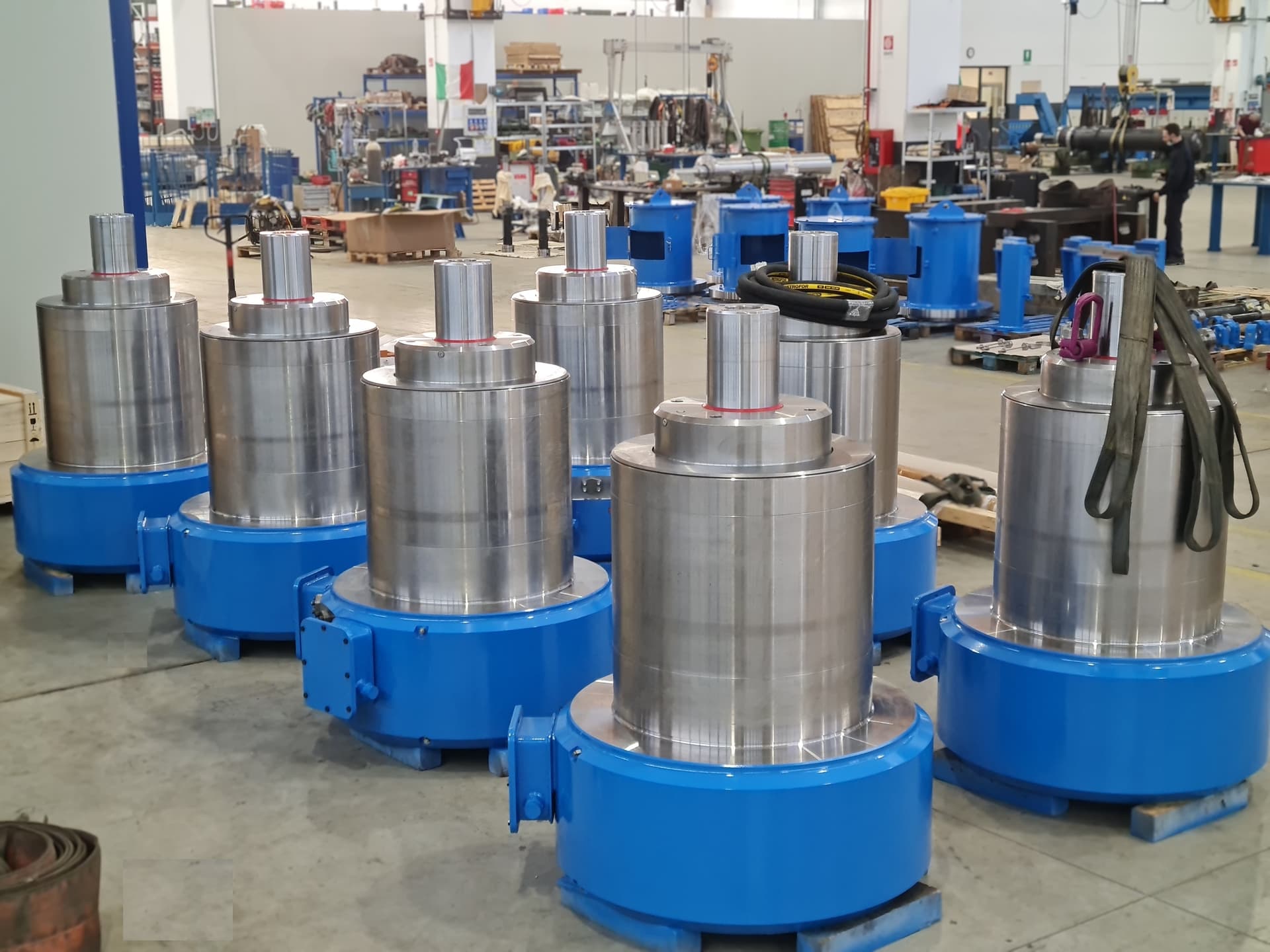 Row of finished blue capsule cylinders with steel pistons in a large workshop