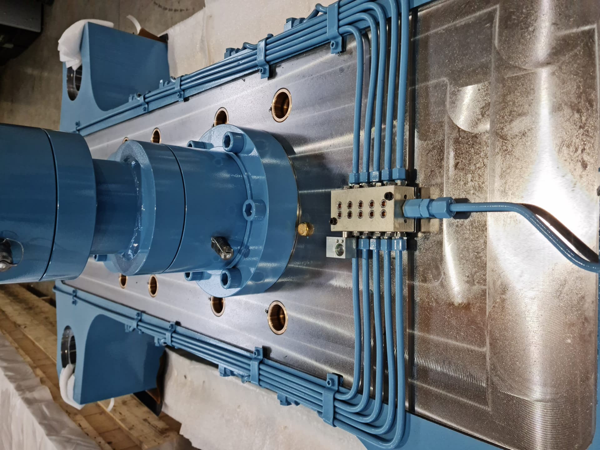 Blue hydraulic cylinder with piping mounted on a steel plate