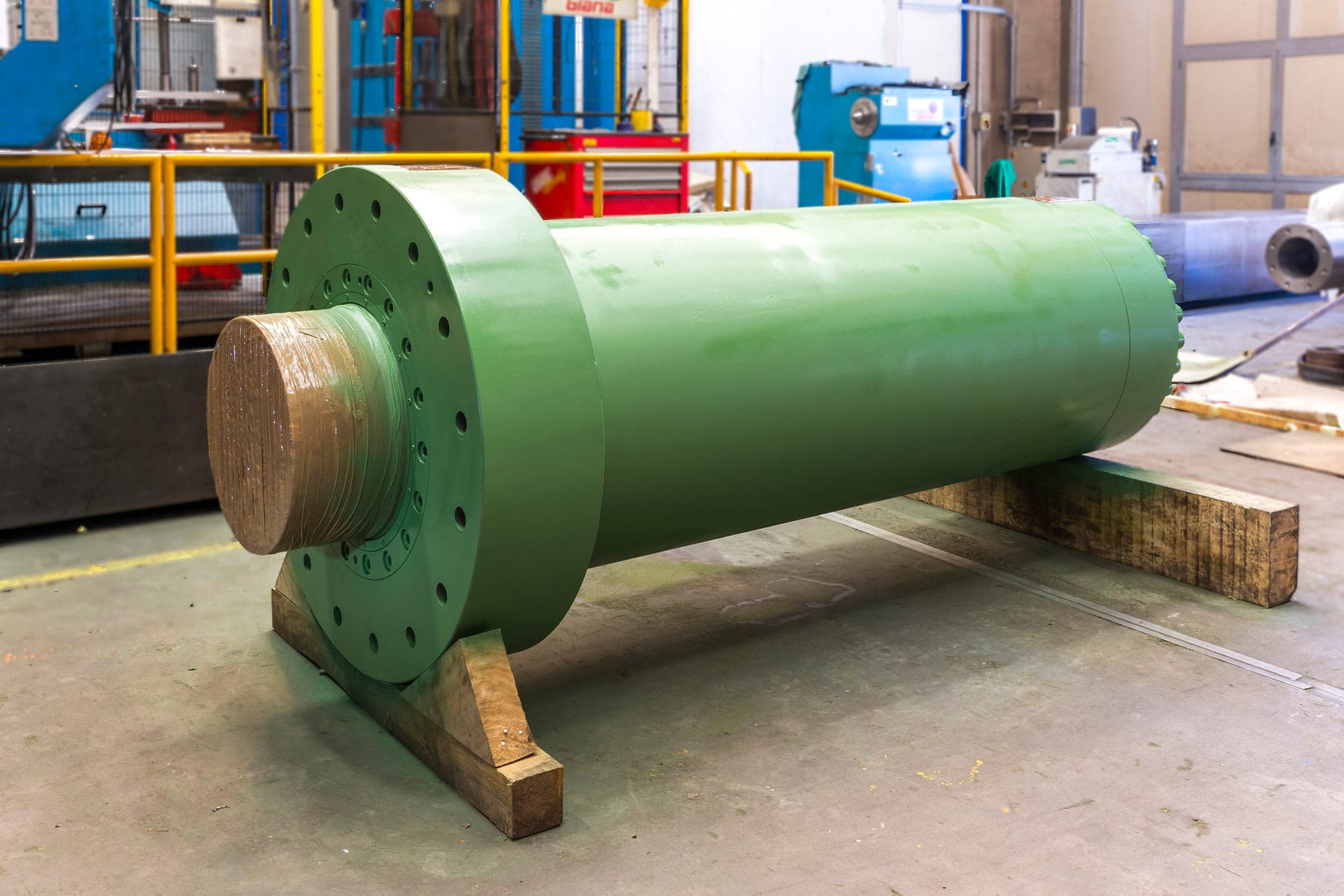 Vérin hydraulique vert avec une grande bride sur des supports en bois