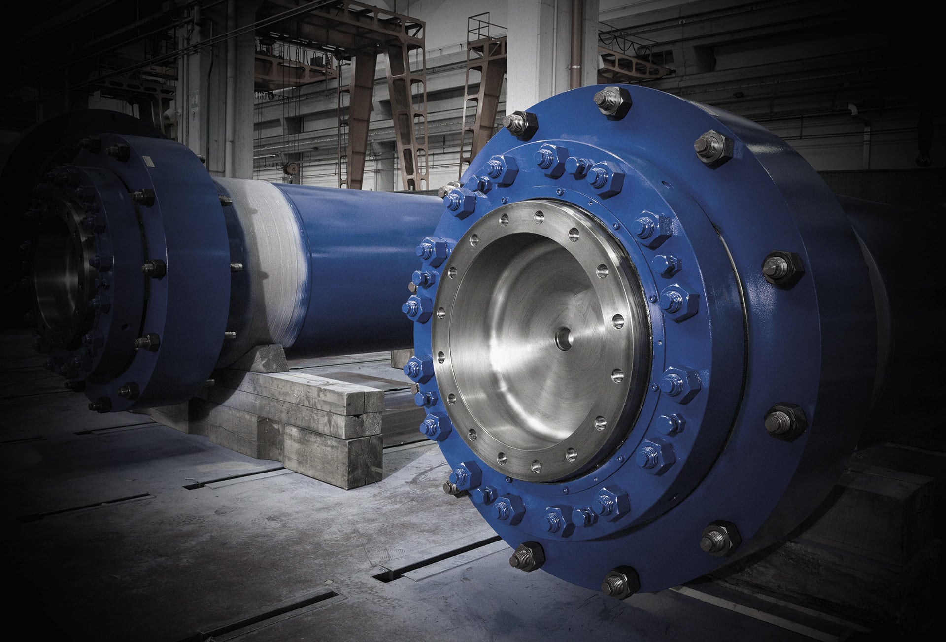 Large blue cylinder with a bolted flange cover and steel piston