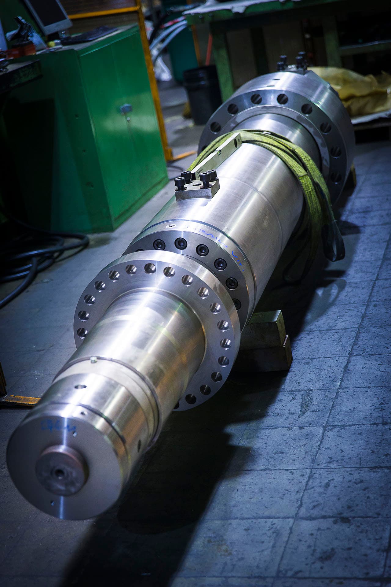 Chromed steel cylinder with a bolted flange on a workshop floor