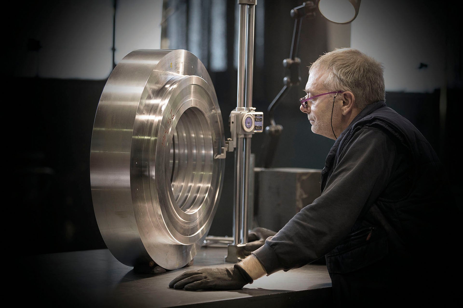 Inspector checking a machined steel part with a measuring column