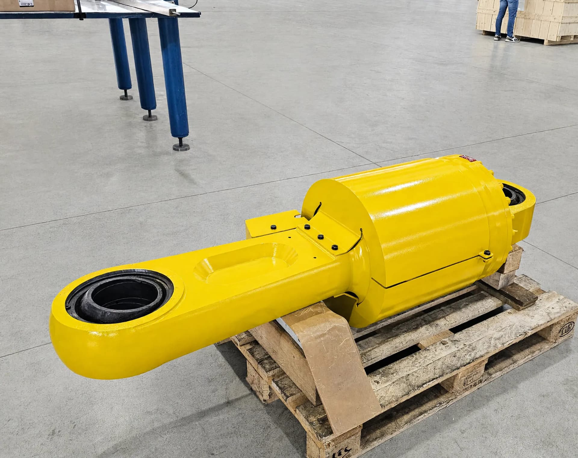 Cilindro idraulico giallo con occhio a snodo sferico, su pallet in officina