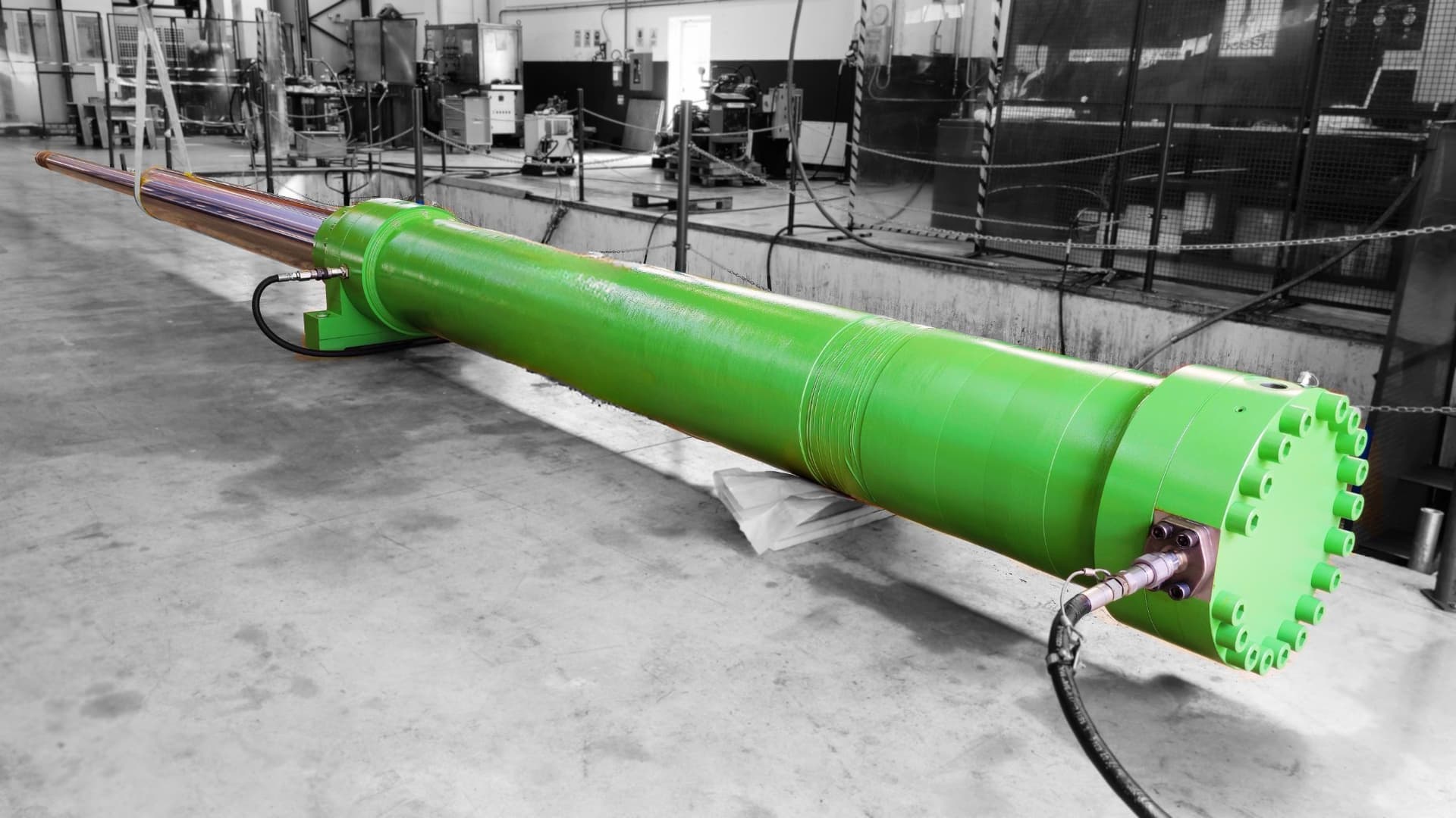 Long green hydraulic cylinder with chromed rod on a workshop floor