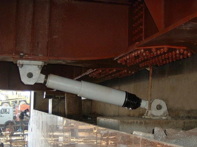Hydraulic seismic device installed under the deck of a bridge
