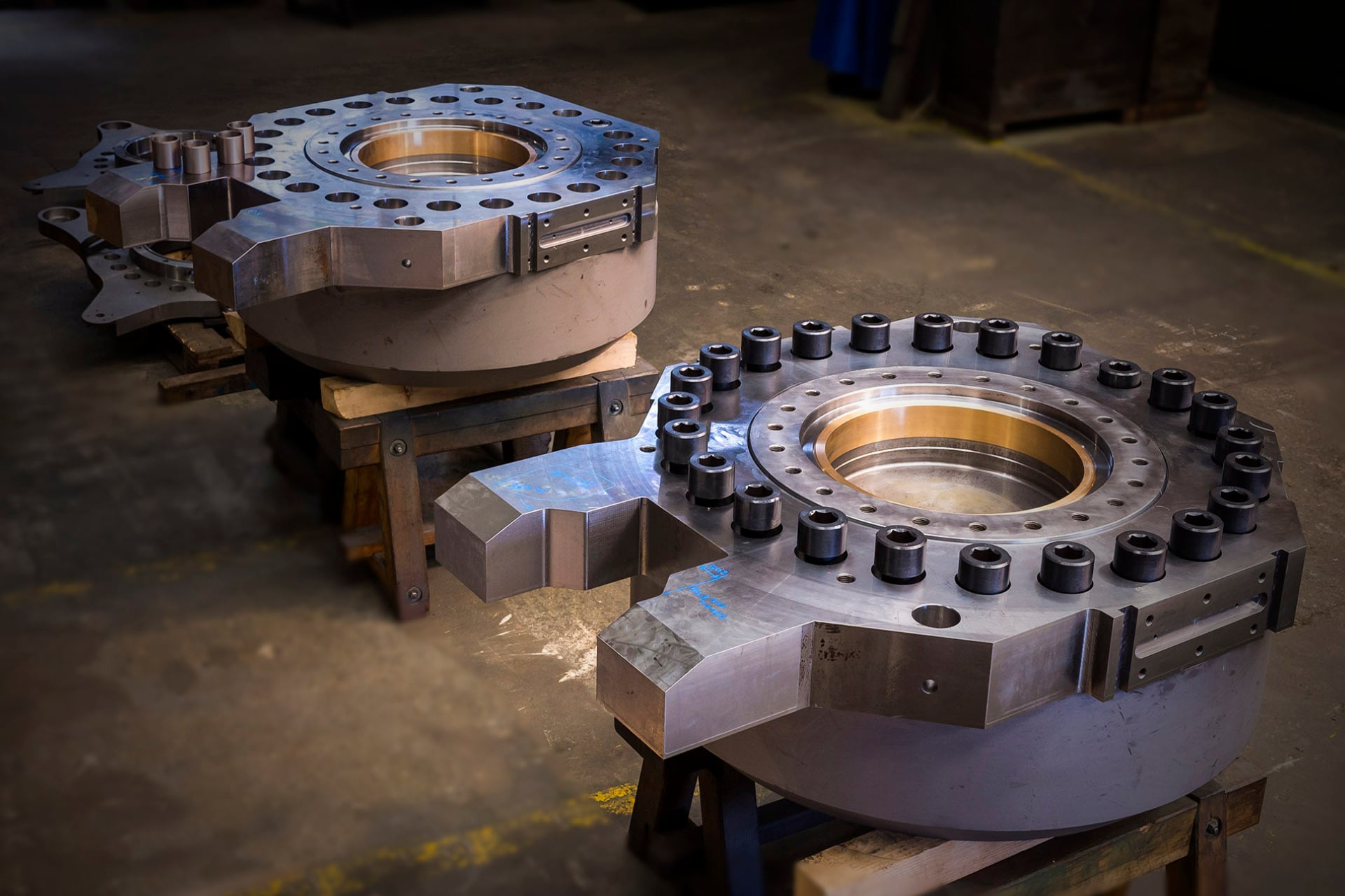 Machined steel capsule bodies with bronze surfaces on a workshop floor
