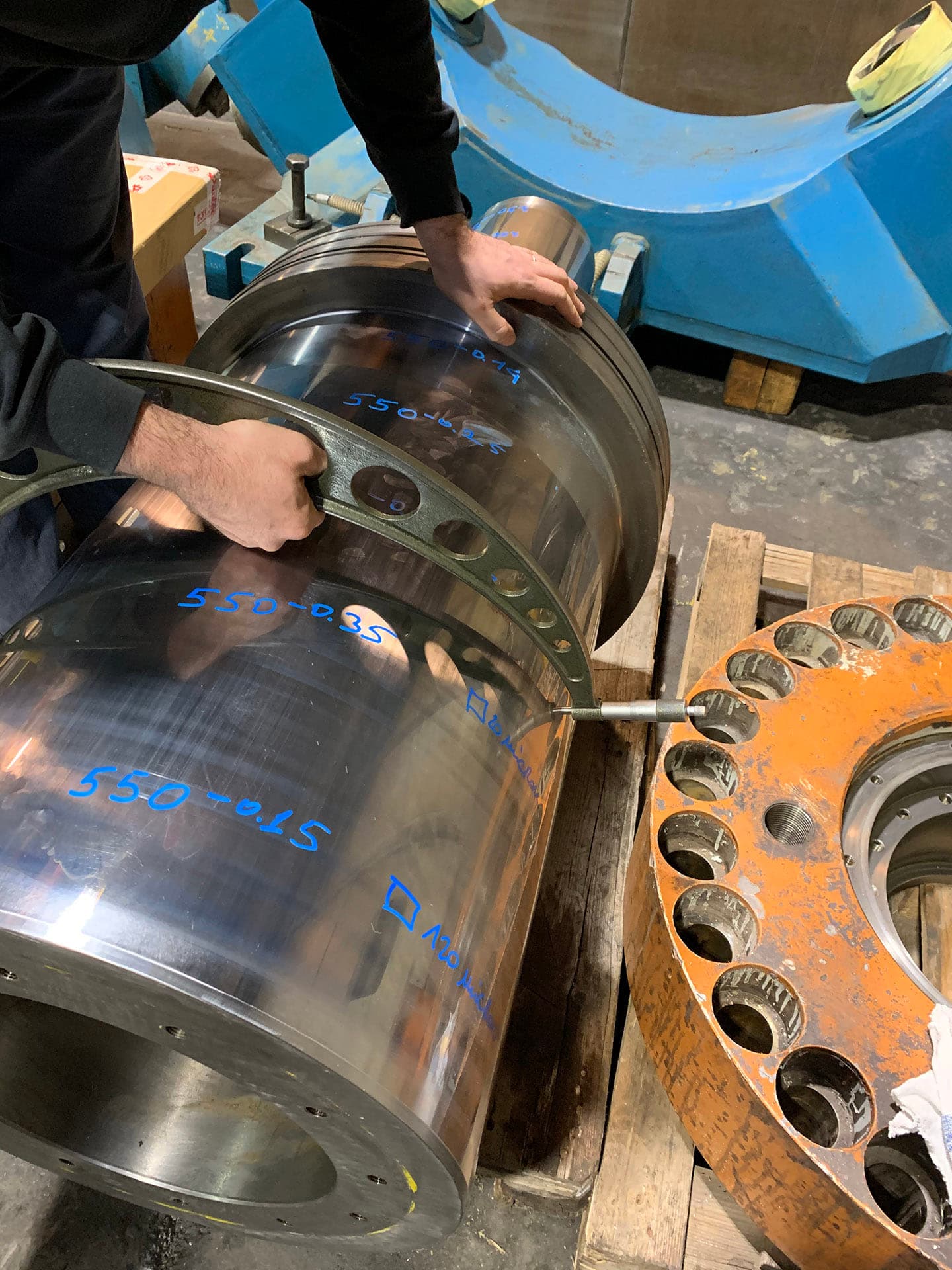 Mains manipulant une bague sur un grand vérin poli avec des repères bleus