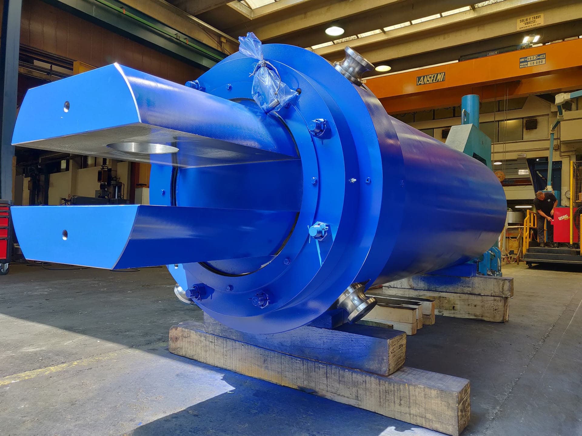 Blue cylinder with a fork-shaped rod end in a workshop