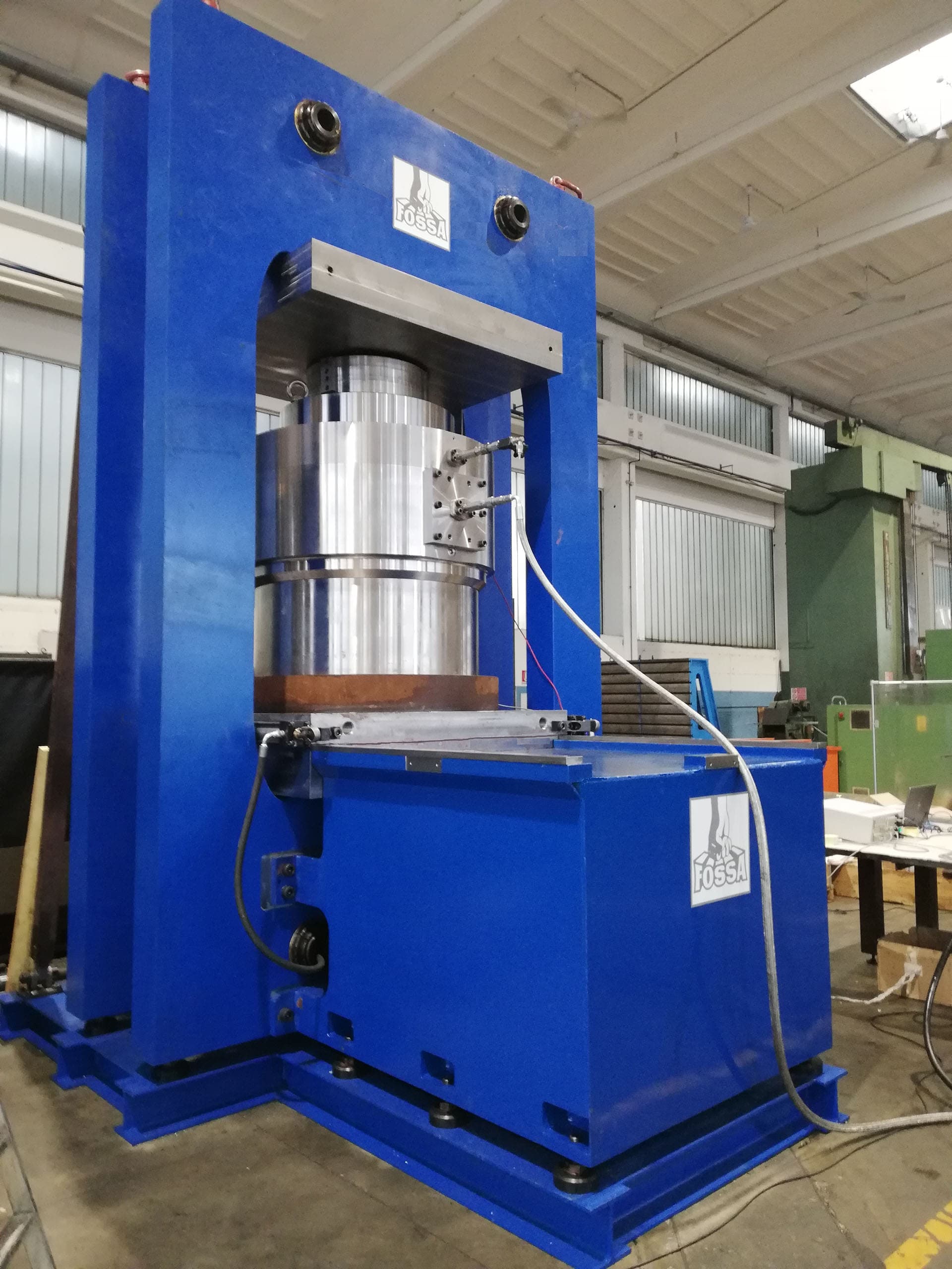 Silver capsule cylinder under test in a blue press frame