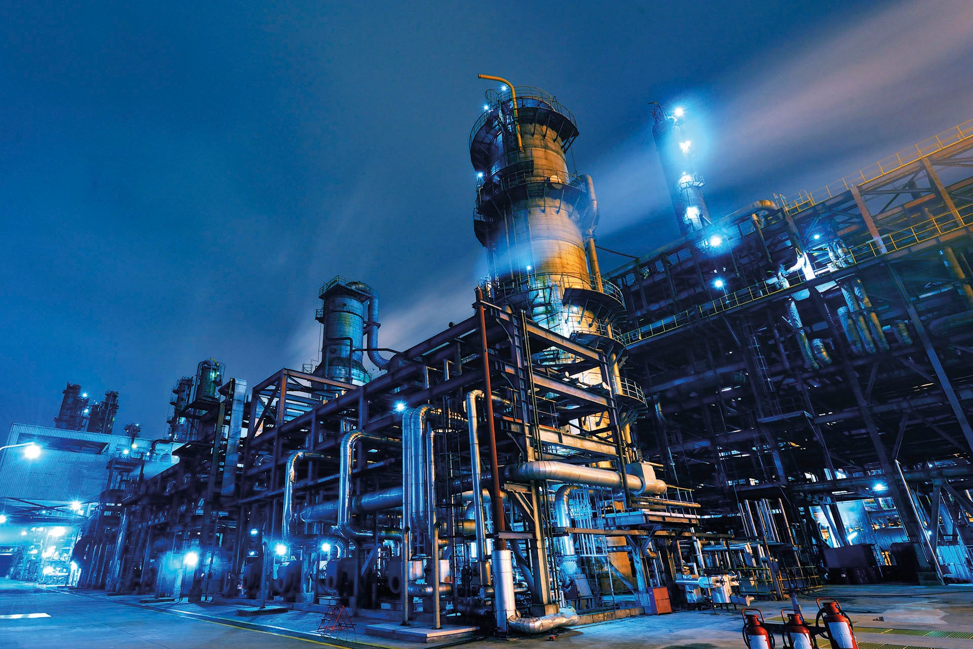 Oil refinery at night with lit towers and pipework