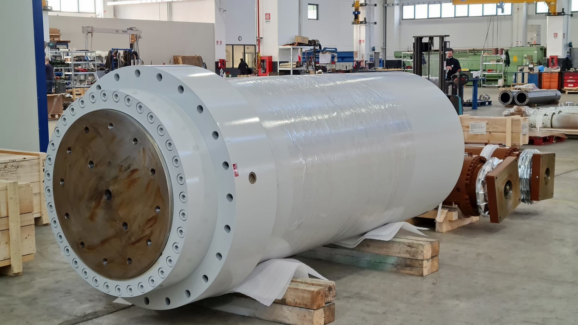 Large white cylinder with a flange on wooden supports in a workshop