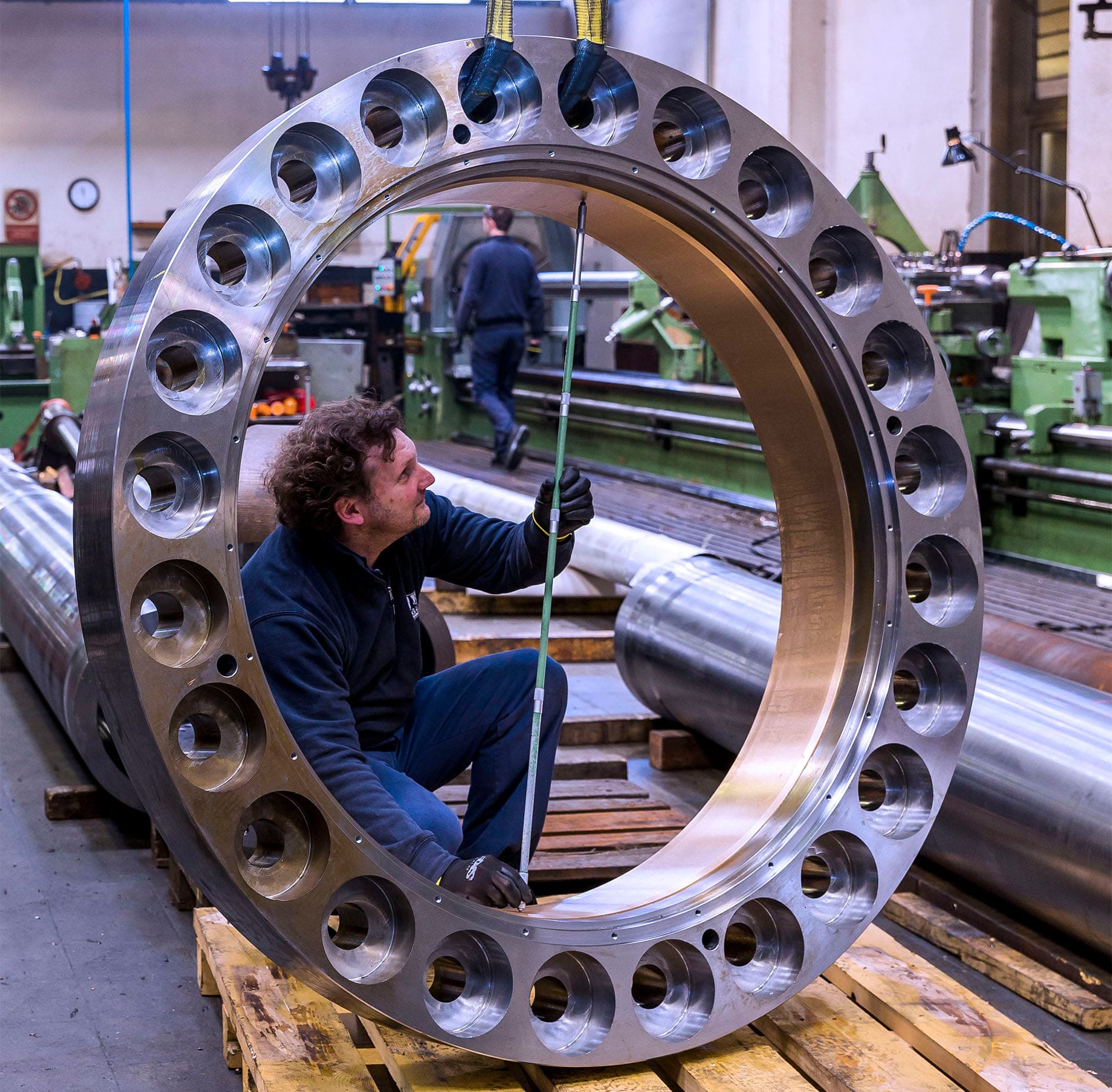 Technician measuring the bore of a large steel ring with bolt holes