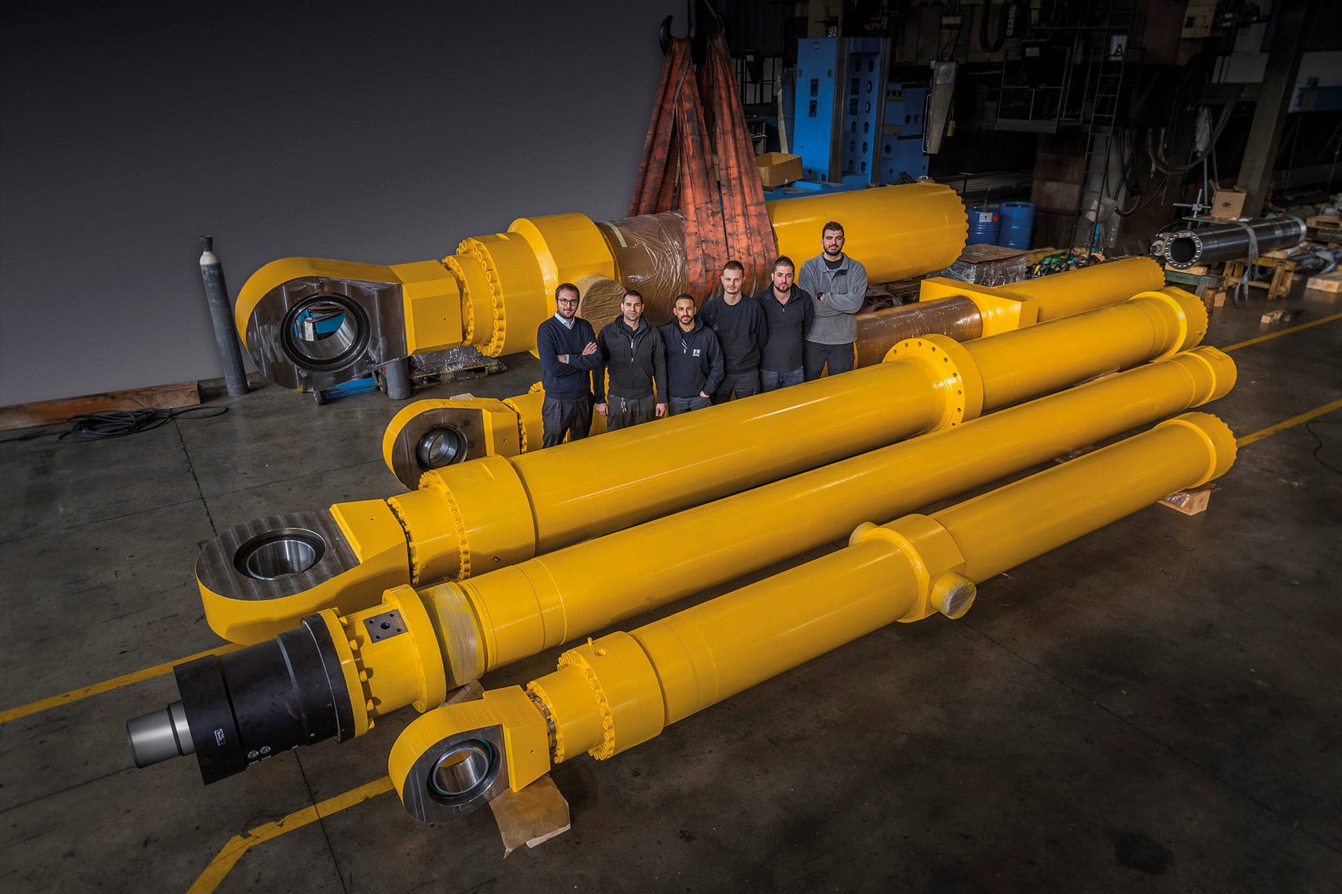 Team of workers standing beside four large yellow cylinders