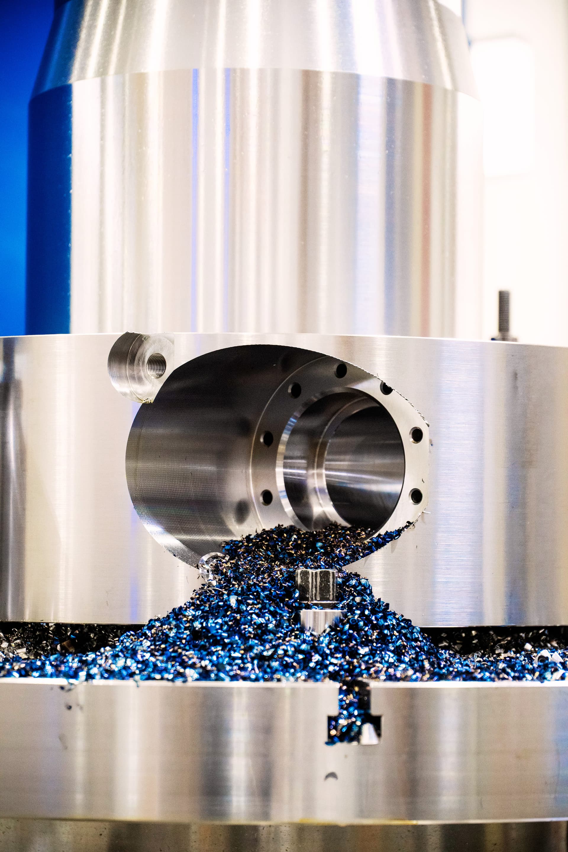 Bloque de acero siendo mandrinado con virutas metálicas azules en una máquina