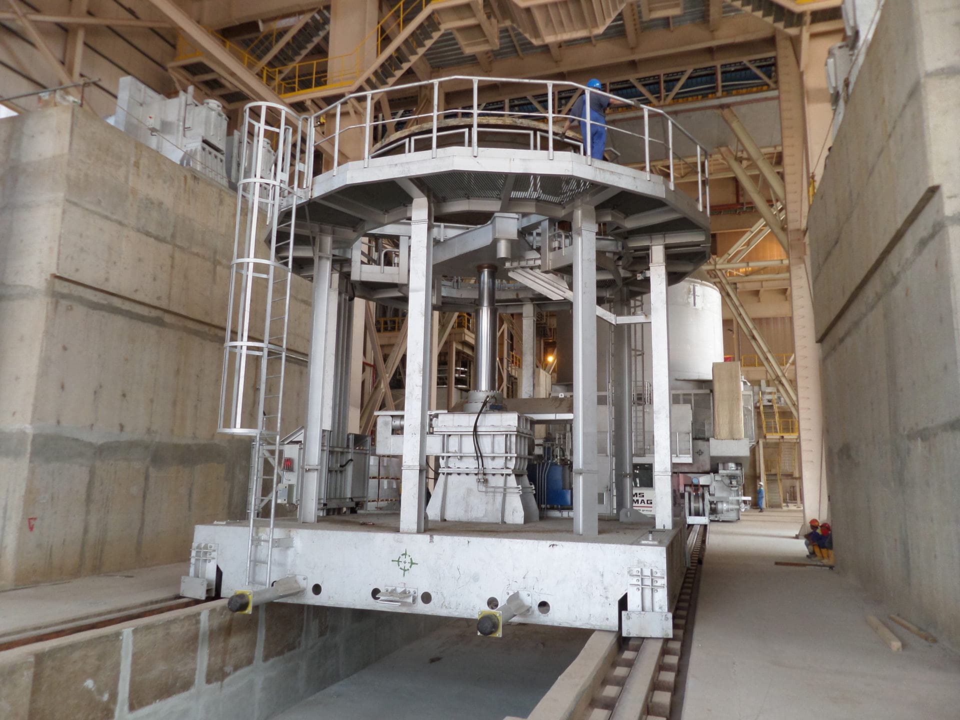 Large white steel structure with a central cylinder inside an industrial hall