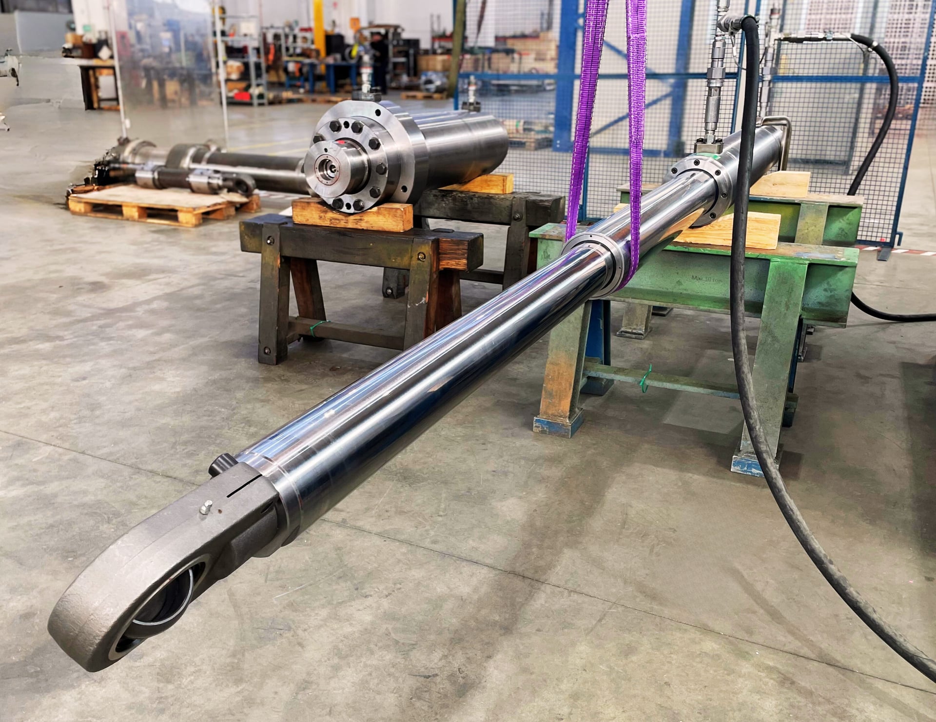 Long telescopic cylinder with a rod eye lifted by a sling in a workshop